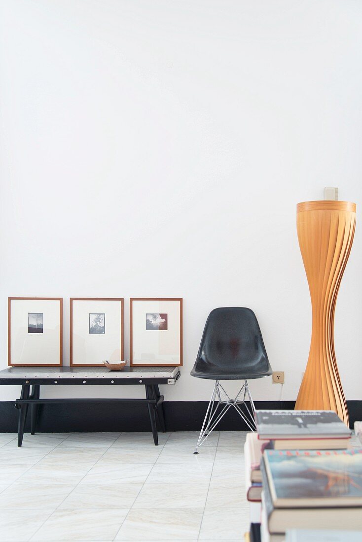 Schwarzer Klassikerstuhl neben Wandtisch mit gerahmten Bildern in Wohnraum mit minimalistischem Retro Flair