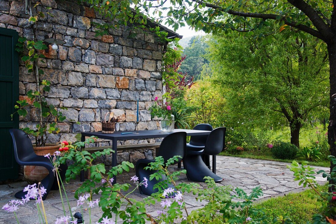 Classic black shell chairs around table on terrace of Italian farmhouse