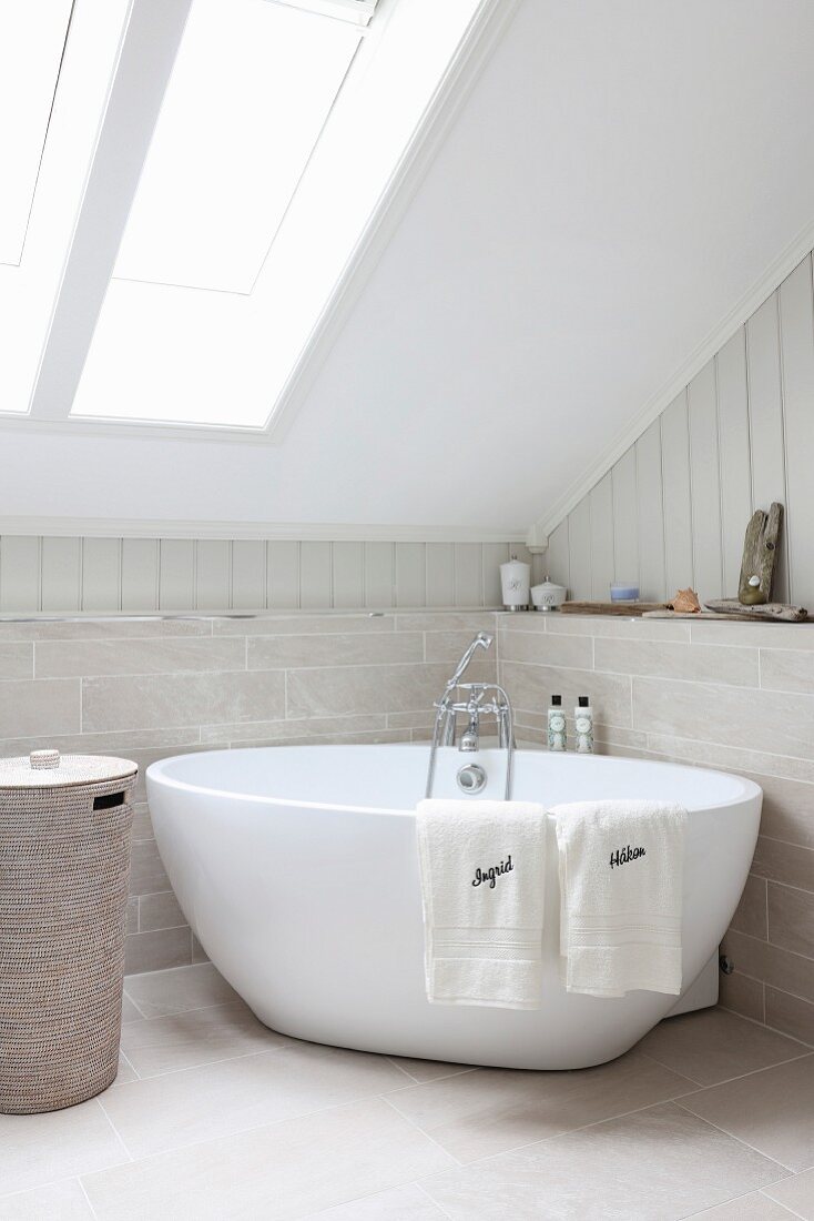 Free-standing bathtub below skylight in sloping ceiling