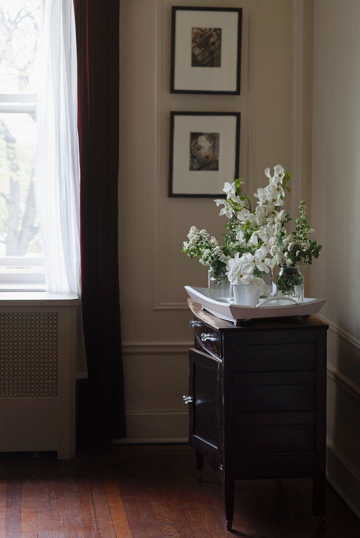 Tray of white flowers on chest of drawers