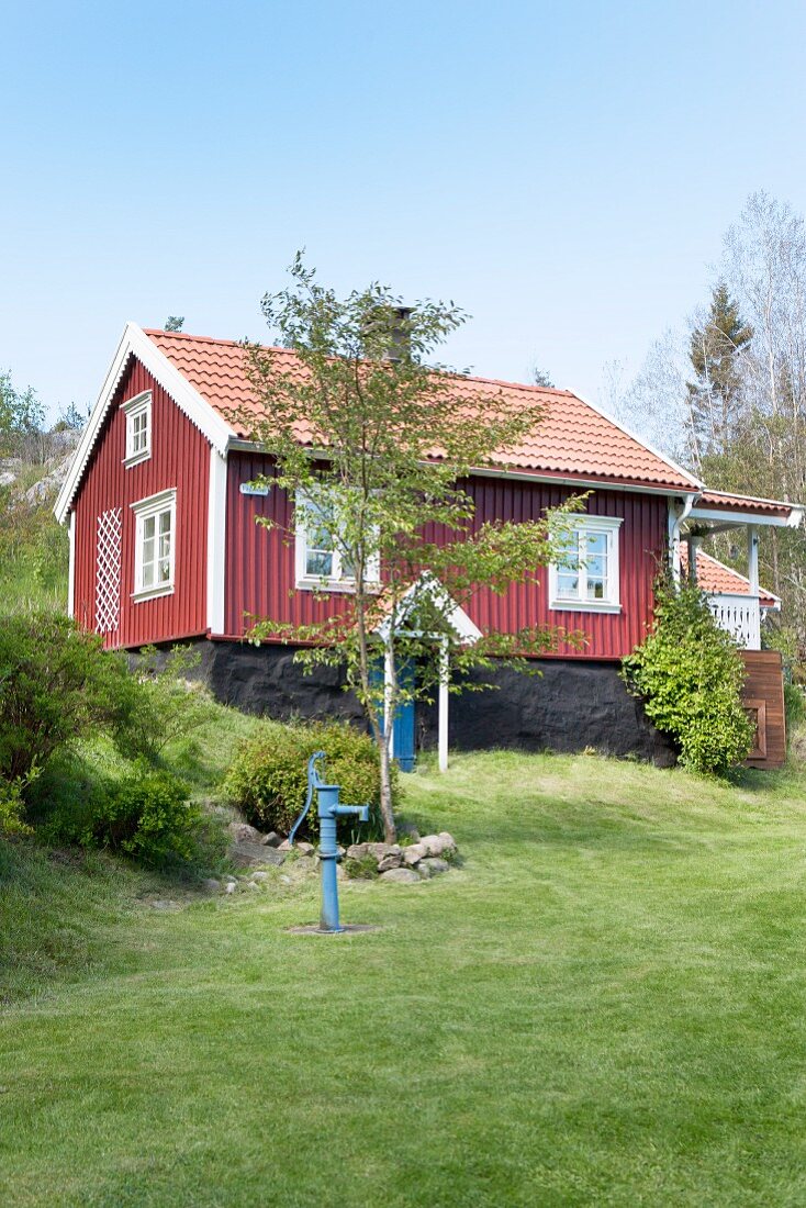 Falu-red Swedish house with white windows below blue sky