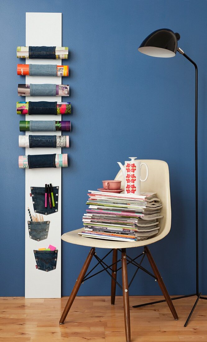 Zeitschriftenhalter aus einem Brett und Jeansstoff an blauer Wand