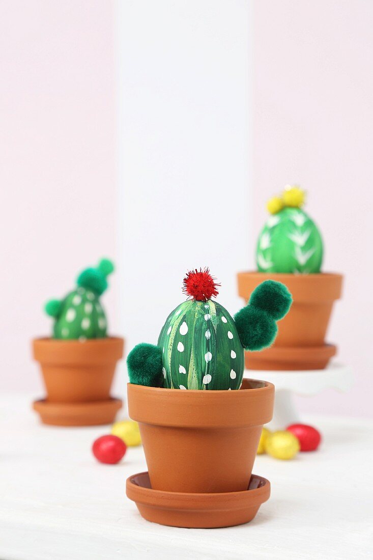Blown eggs painted and decorated to look like cacti in terracotta pots