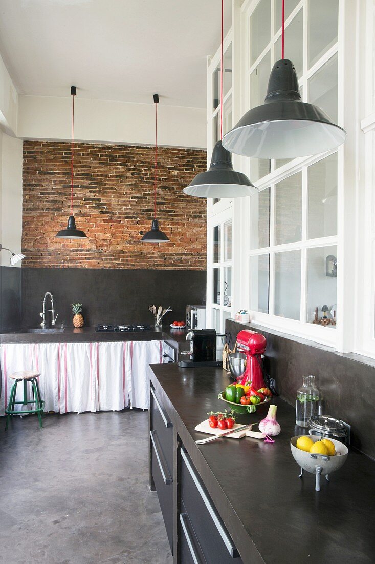 Schwarze Küchenzeilen in Loftwohnung mit Ziegelwand und poliertem Betonboden