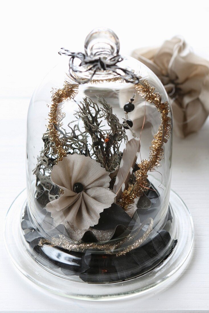 Christmas arrangement of fabric flowers and moss under glass cover