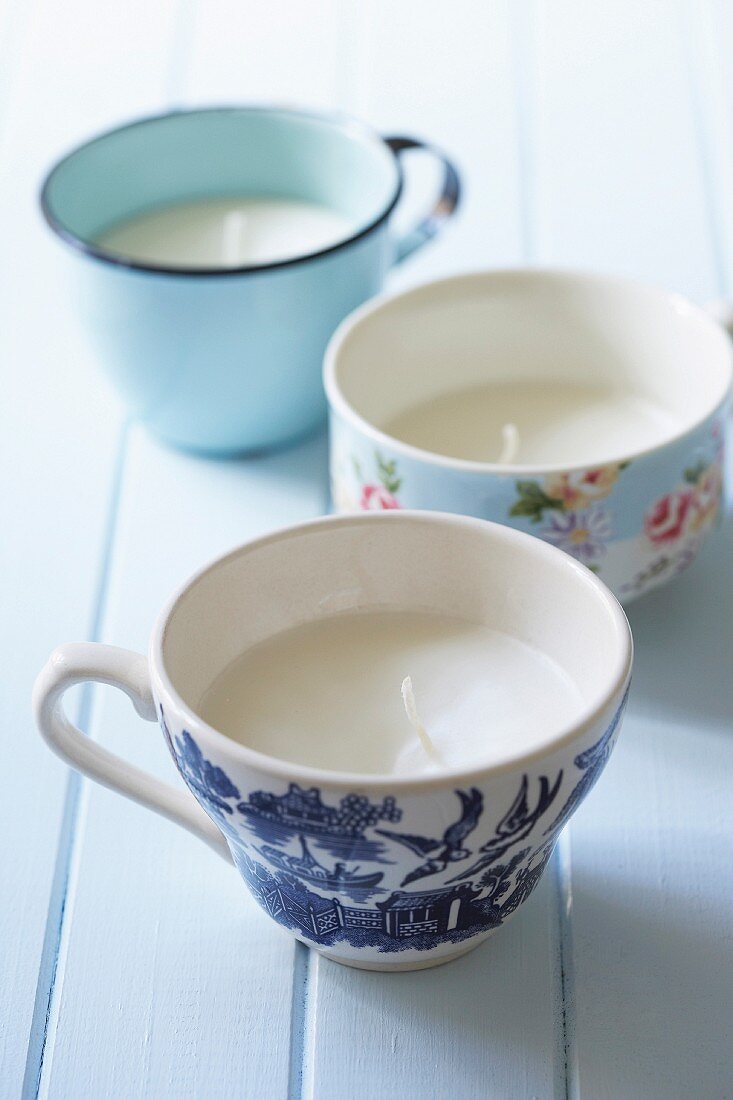 Hand-poured candles in various teacups with vintage patterns