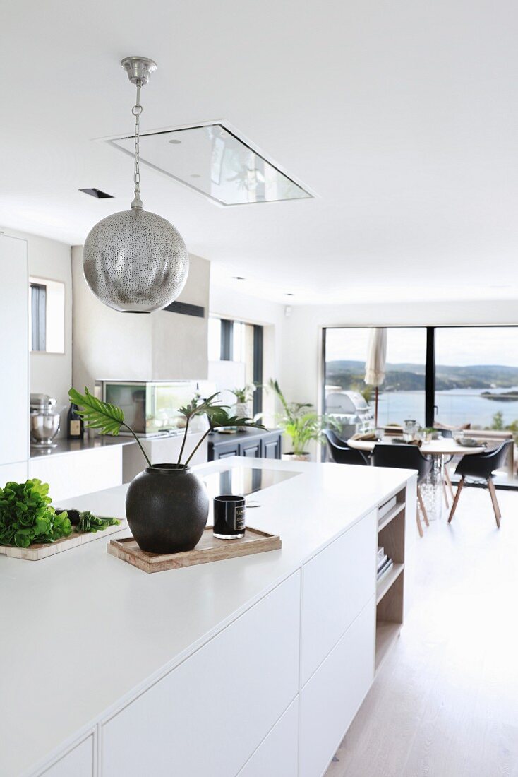 weiße Kücheninsel und Kugelleuchte in offenem Wohnbereich mit Landschaftsblick