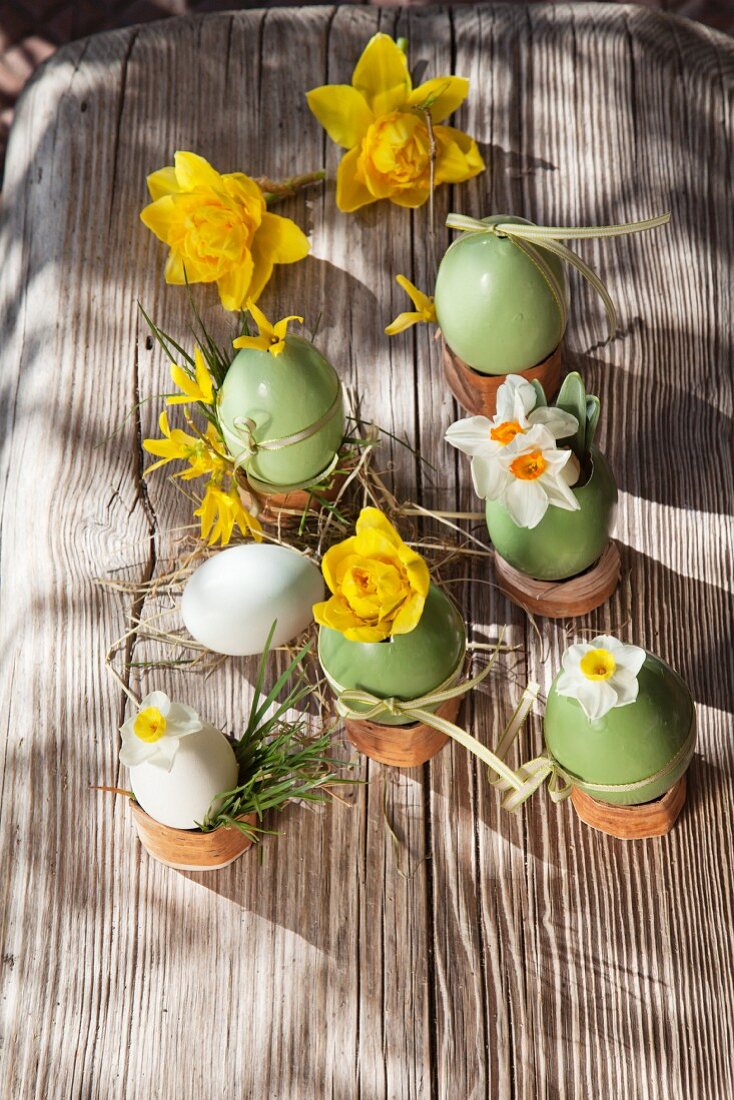 Painted Easter eggs used as vases for narcissus on old board
