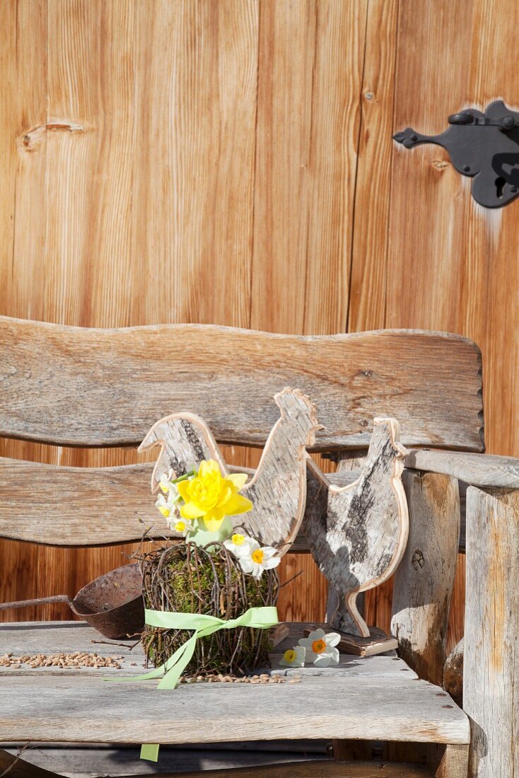 Two wooden hens and Easter flower arrangement on bench