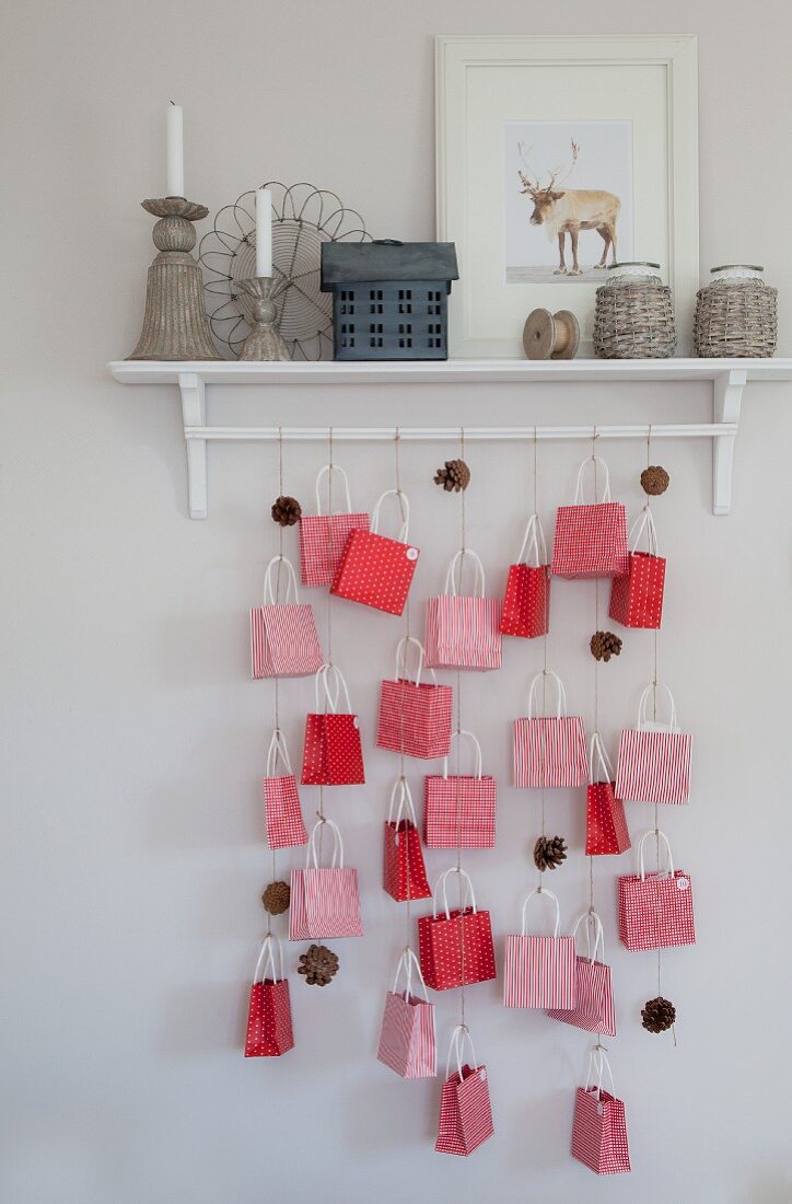 Advent calendar made from paper bags and fir cones hung from wall-mounted shelf