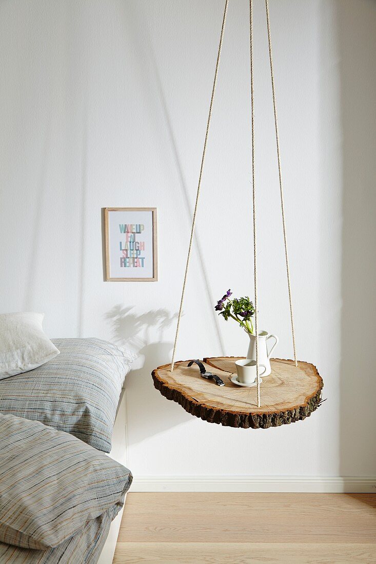 Slice of tree trunk hung from ropes and used as bedside table