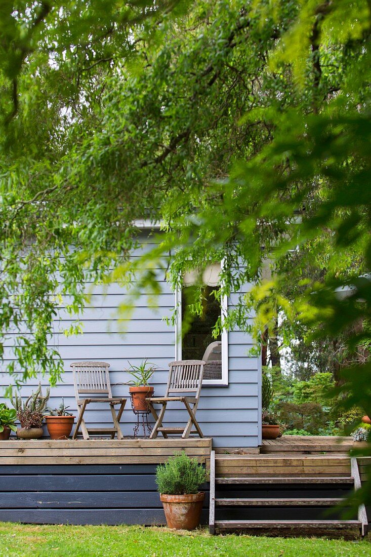 Blick auf Terrasse mit Gartenstühlen vor Holzhaus