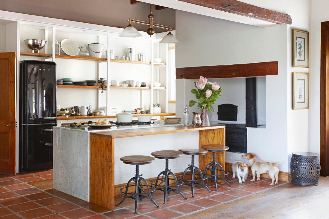 Counter and bar stools in open-plan kitchen with terracotta floor tiles