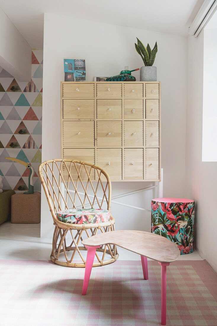 Wicker chair and upcycled side table in cosy seating area of bright bedroom