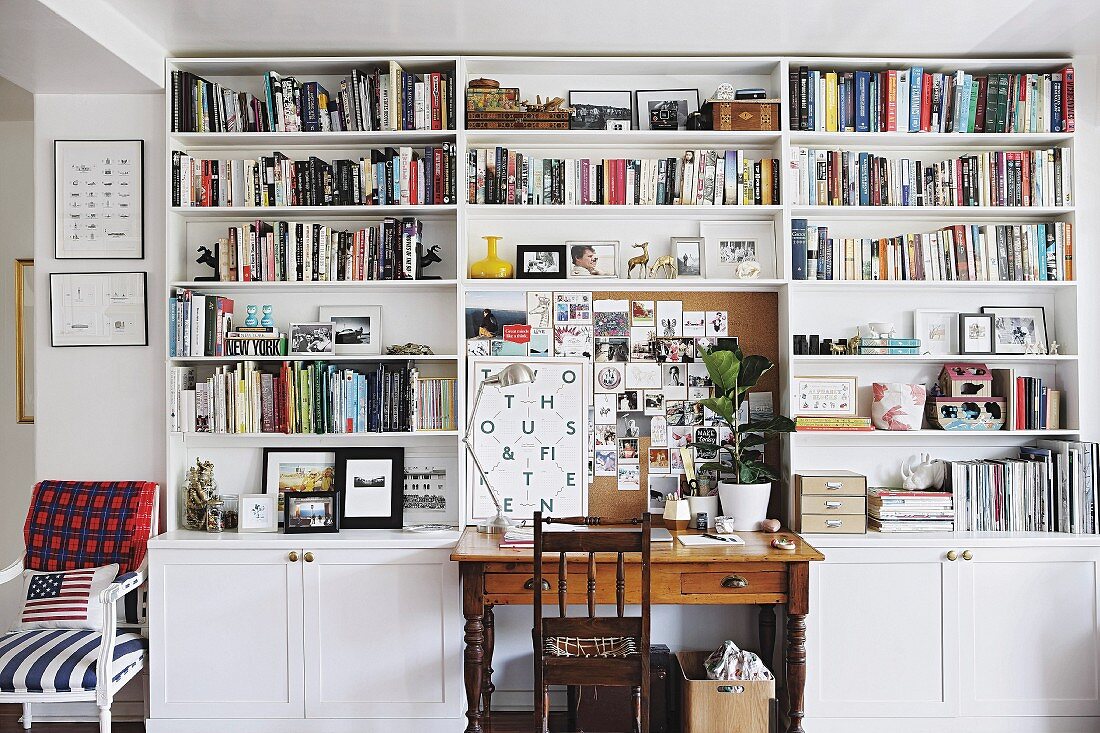 Vintage desk and wooden chair surrounded by white bookcase
