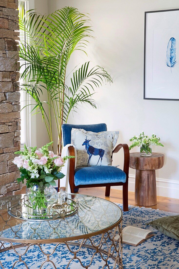 Blue armchair, palm tree and glass table in corner of room