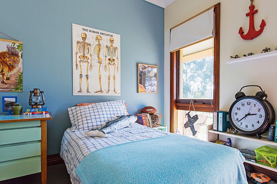 Jungenzimmer mit 'Skelett-Plakat' an blauer Wand und Bett mit blau-weisser Bettwäsche