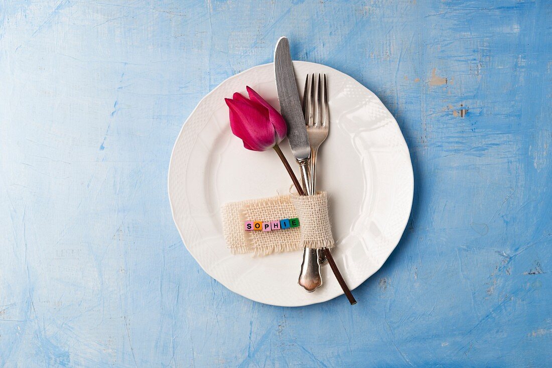 Cutlery, tulip and name tag on plate