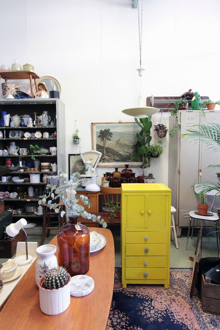 Various flea-market finds and vintage items around yellow-painted wooden chest of drawers
