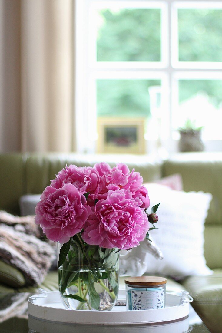 Pink peonies in glass vase on coffee table