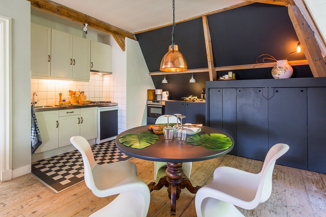 Schalenstühle um runden Esstisch in moderner Küche mit rustikalem Dielenboden