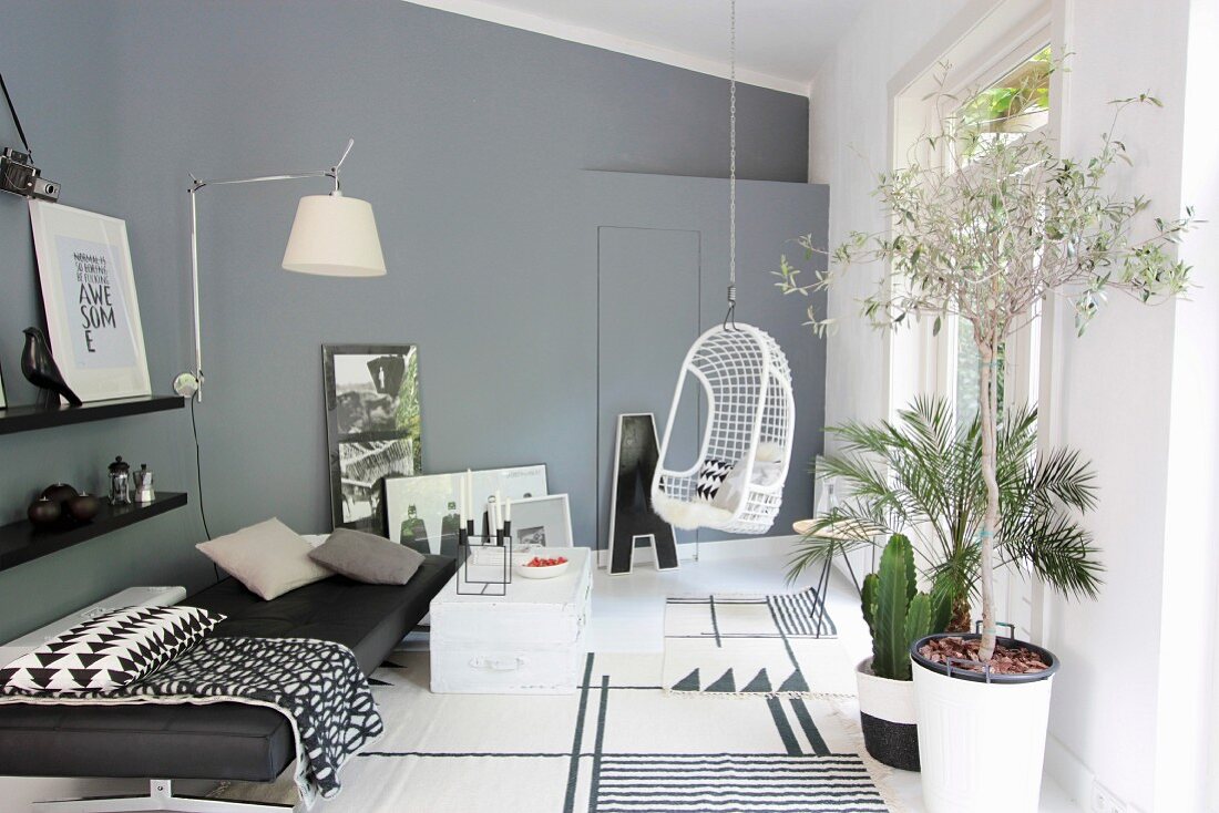 Modernes Wohnzimmer in Grautönen, mit Tagesbett, Hängestuhl, Wandleuchte und Pflanzen