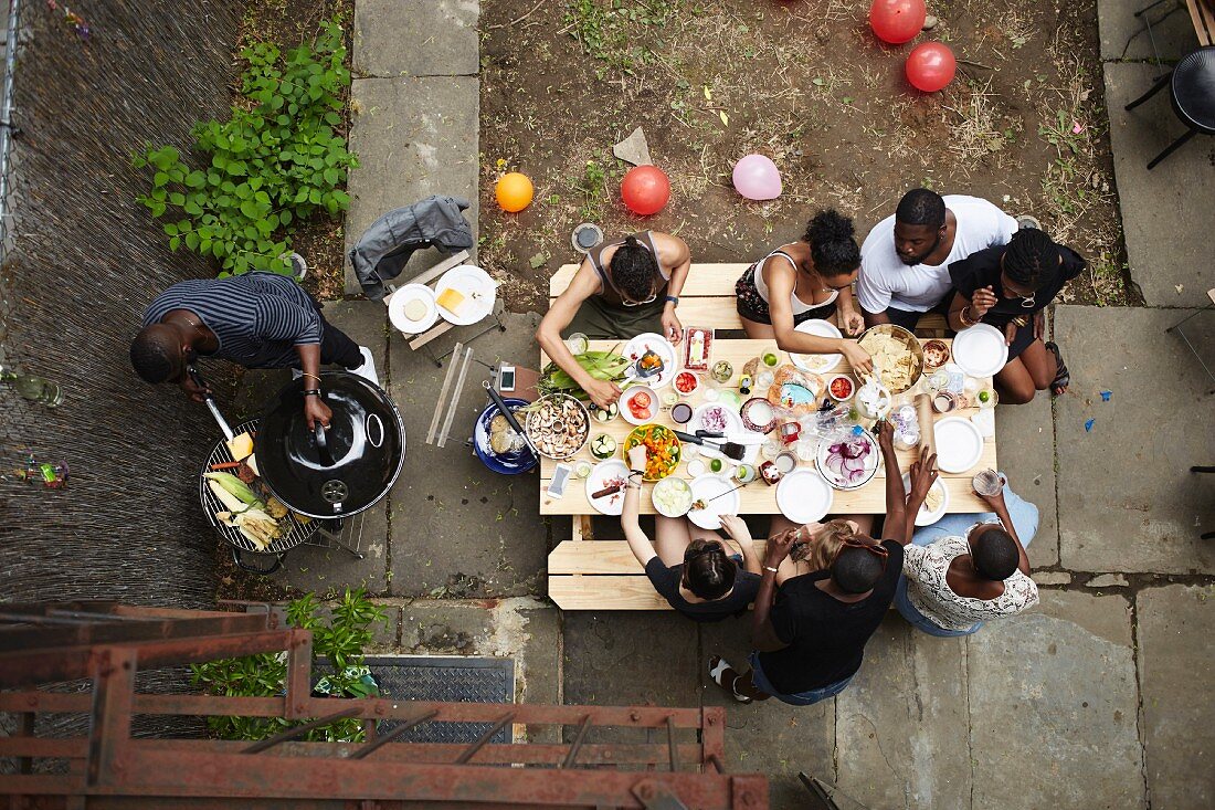 Blick von Oben auf Gruppe von jungen Leuten beim Grillen im Hinterhof