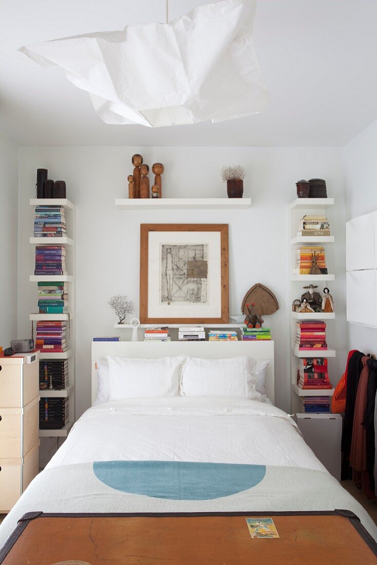 Kleines Schlafzimmer mit Bücherregalen rund ums Betthaupt
