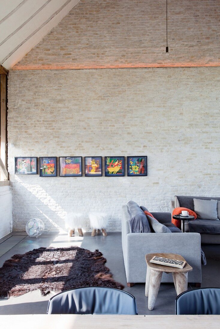 Grey sofa set and colourful artworks on brick wall in converted barn