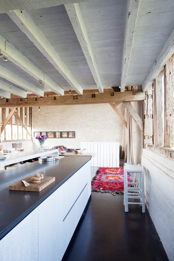 Elegante Kücheninsel in umgebauter Scheune mit rustikaler Holzbalkendecke