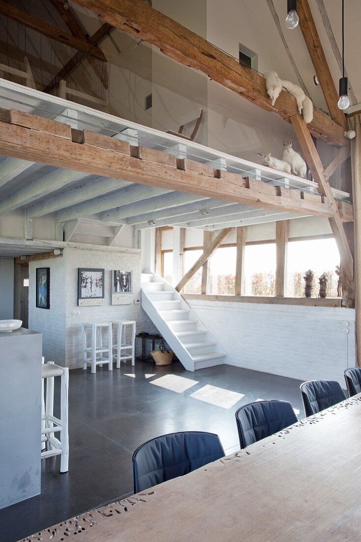 White staircase next to window in converted barn with mezzanine level