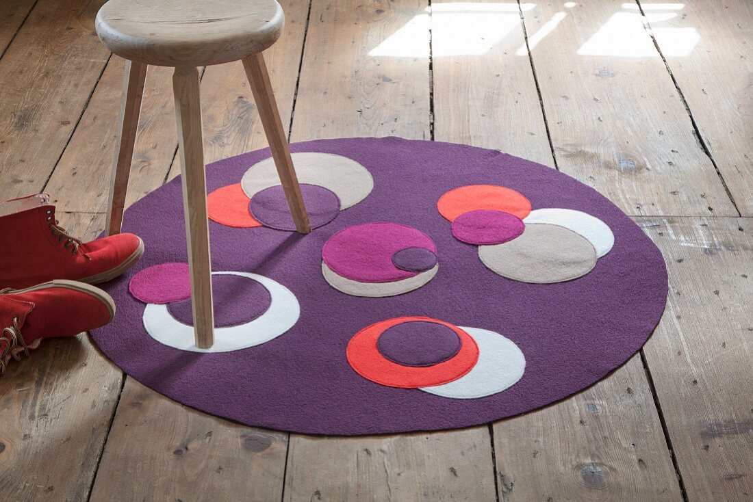 Round, purple, boiled-wool rug with contrasting appliqué circles