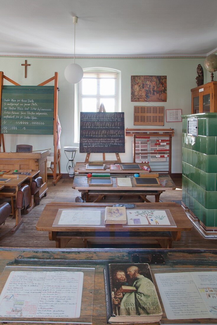 Klassenzimmer mit Tafeln, nostalgischen Schulbänken und aufgeschlagenen Heften in Schulmuseum