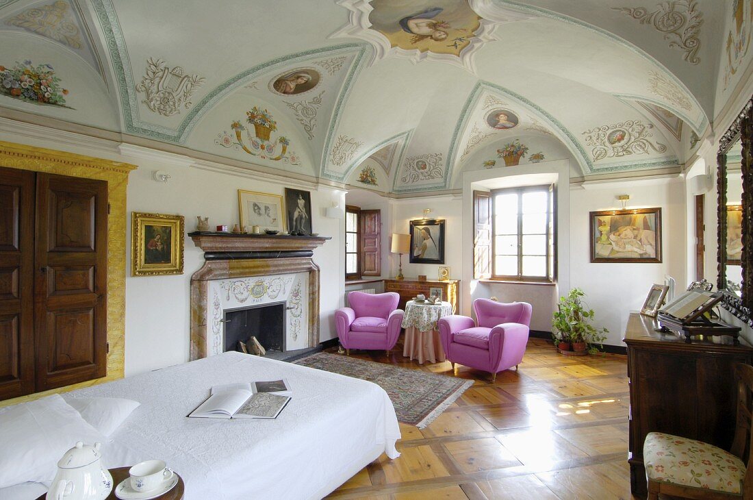 Pink armchairs in bedroom of elegant old villa with painted frescoes