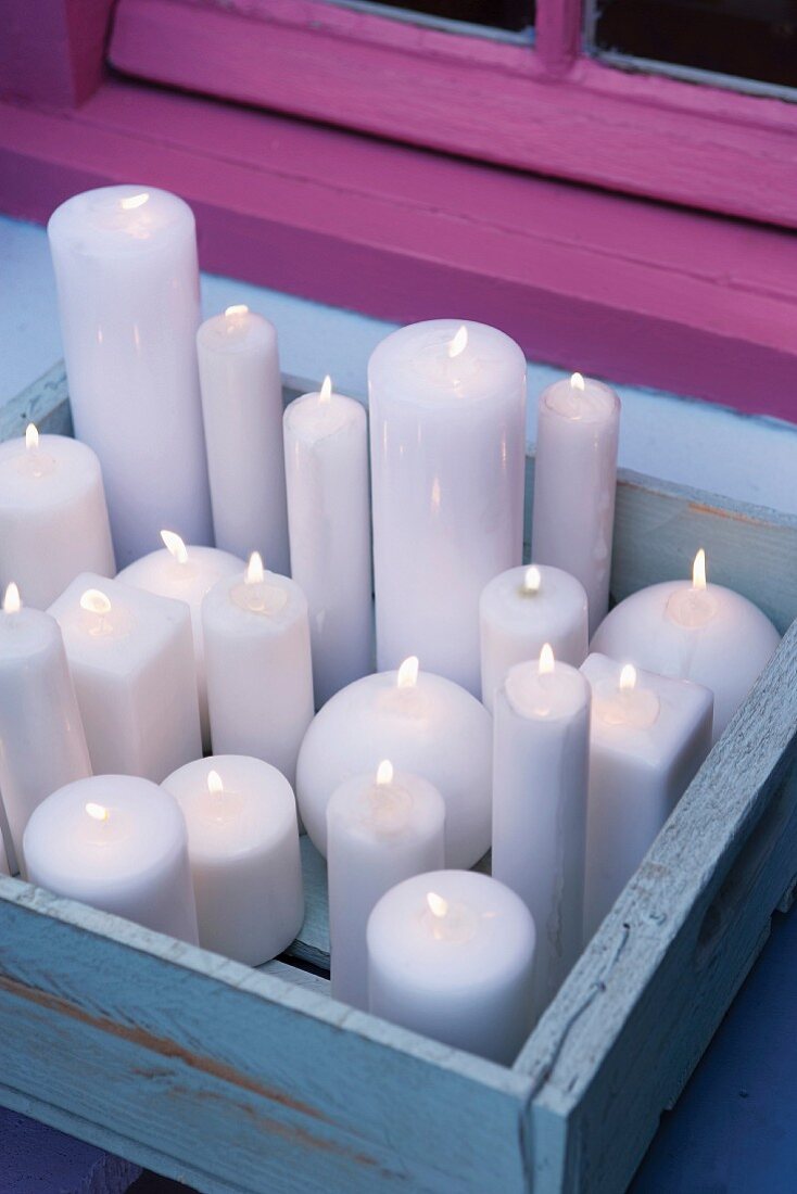 Lit white candles in blue-painted wooden crate