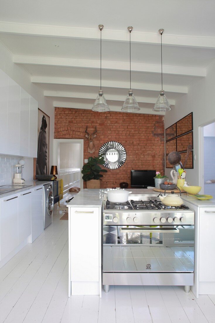 Open-plan kitchen with white floor and brick wall