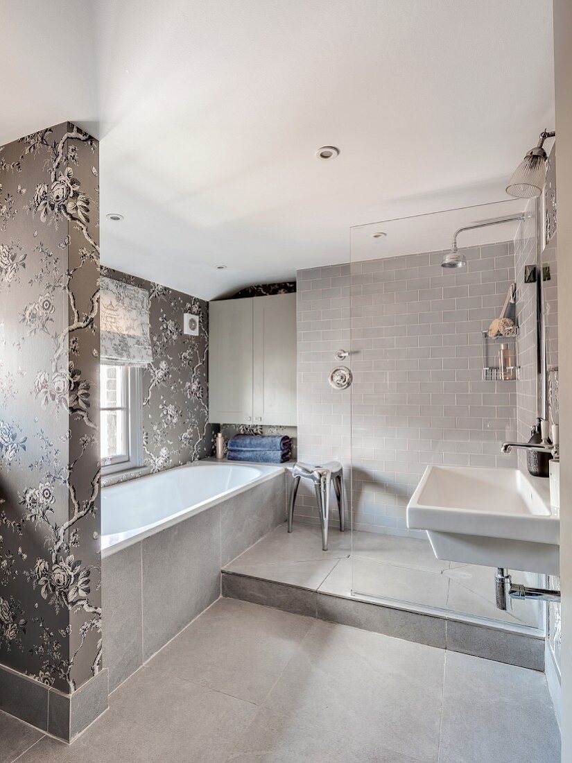 Elegantes Bad in Grautönen mit Dusche und floraler Tapete im Badewannenbereich