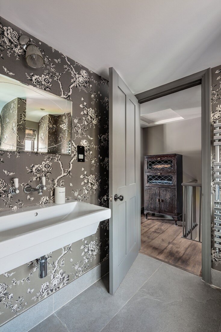 Elegant bathroom with floral wallpaper and view of hallway