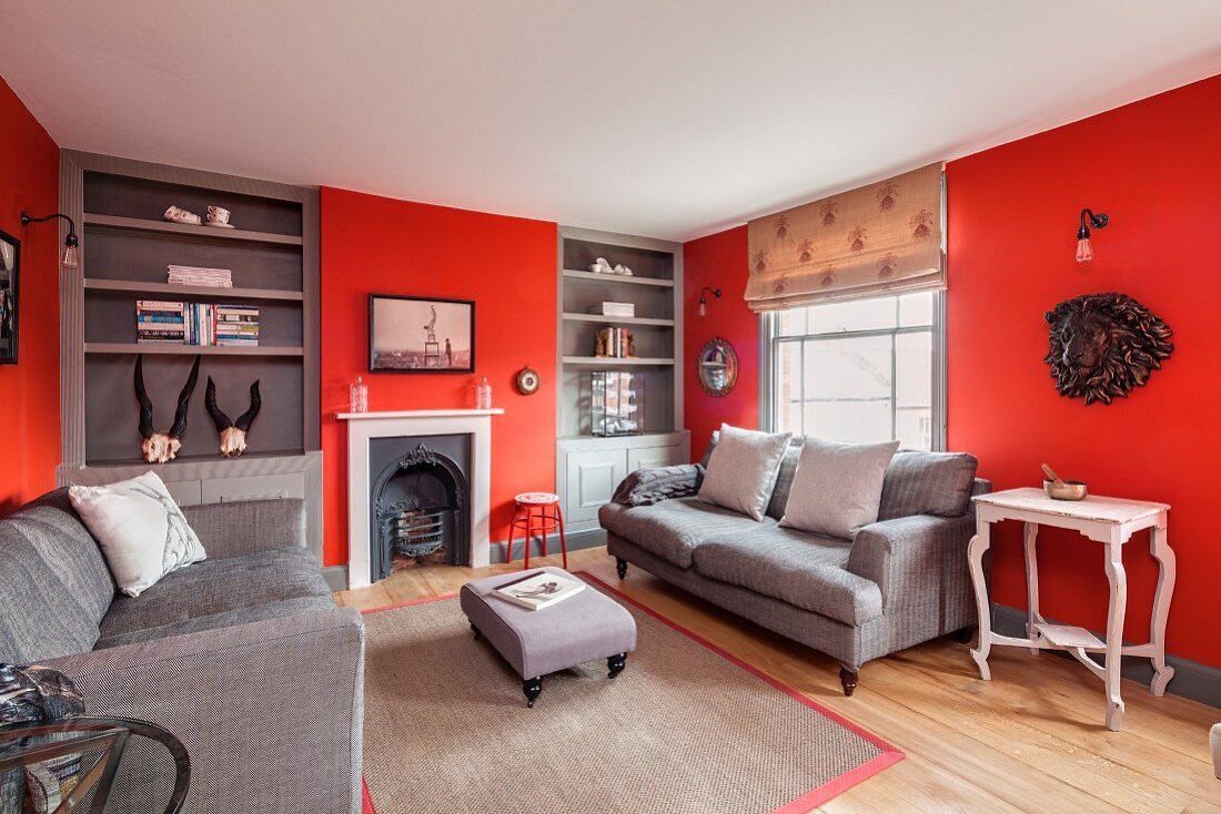 Elegantes Wohnzimmer mit roten Wänden, Einbauregalen und offenem Kamin