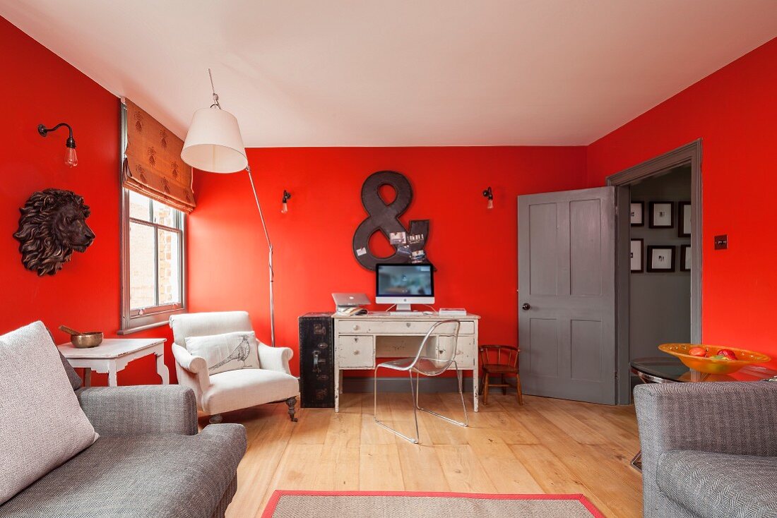 Desk and armchairs against red walls in renovated period apartment