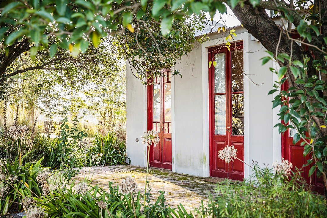 Blick durch Bäume auf Haus mit roten Türen
