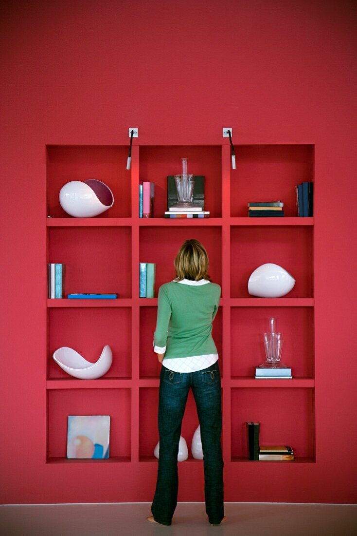Back view of woman standing in front of red fitted shelving