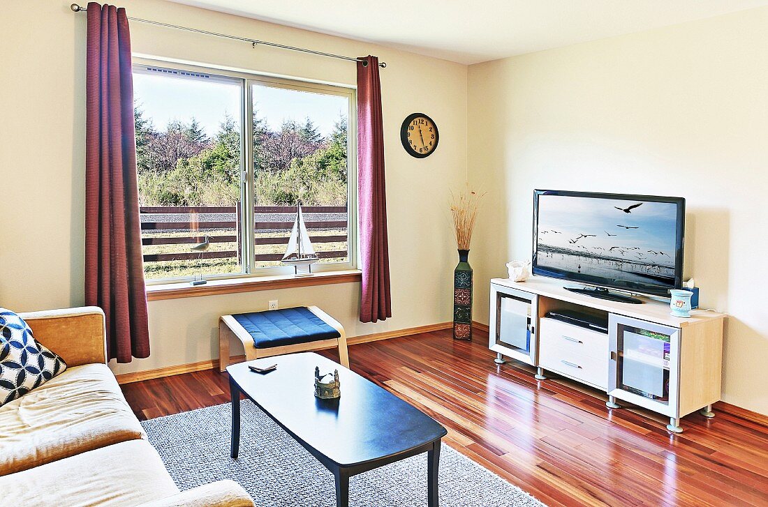 Sofa und Couchtisch vor Hifi-Möbel mit Flachbildfernseher in modernem Wohnzimmer