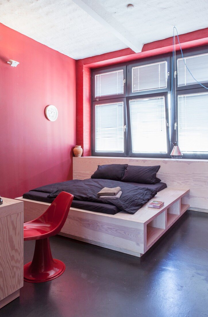 Red minimalist bedroom; custom double bed with elegant storage solution in base below window