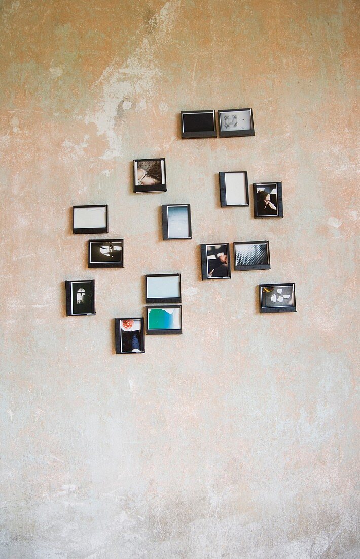 Fotos hängen in Plastikkästen an einer abgenutzen Wand