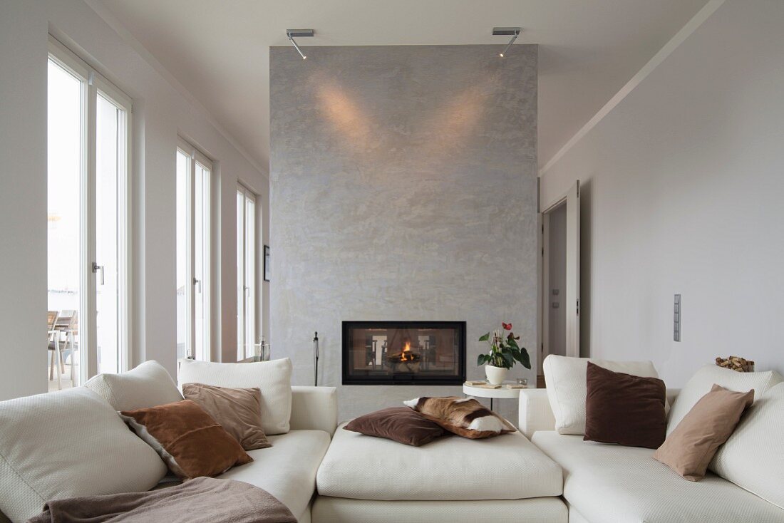 Modernes Wohnzimmer mit weißem Sofa, Raumteilerwand mit Kamin