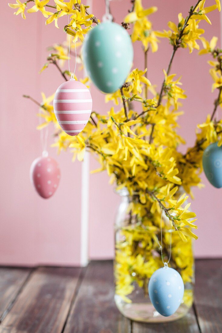 Jar of forsythia decorated with colourful Easter eggs
