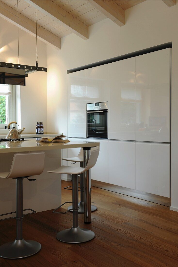 Moderne, weiße Hochglanz-Küche mit Holzboden