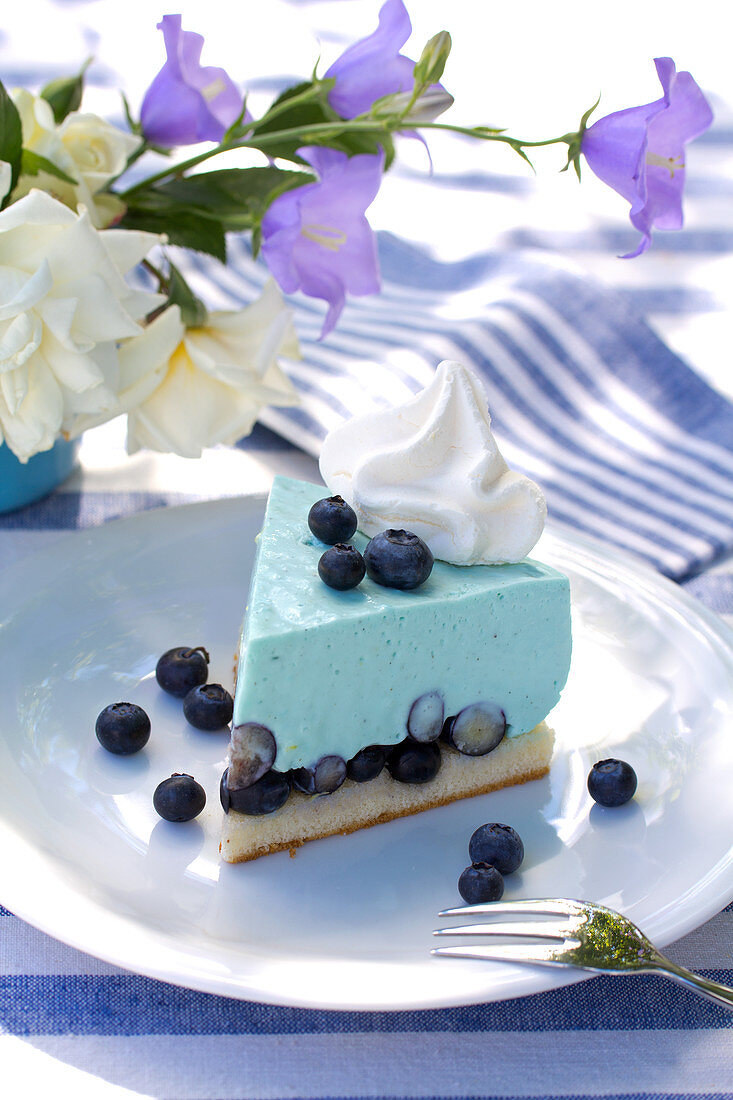 Slice of blueberry mousse tart on table set in blue and white