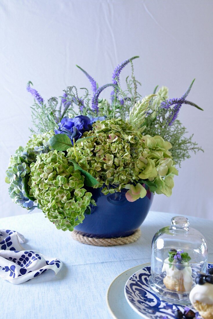 Profiteroles mit Blumenarrangement in blauer Vase